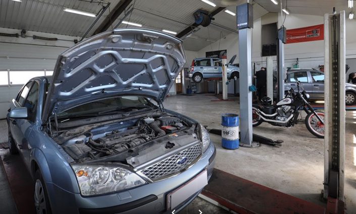 Biler og motorcykel på værksted